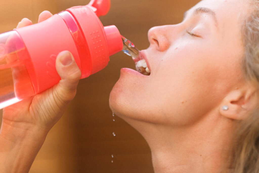 Crop thirsty sportswoman drinking water from bottle Is Mineral Water Acidic?