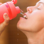 Crop thirsty sportswoman drinking water from bottle Is Mineral Water Acidic?