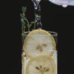 Is Seltzer Water The Same As Tonic Water Person pouring liquid from glass jug into glass with lemon