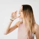 Young woman drinking glass of cold pure water