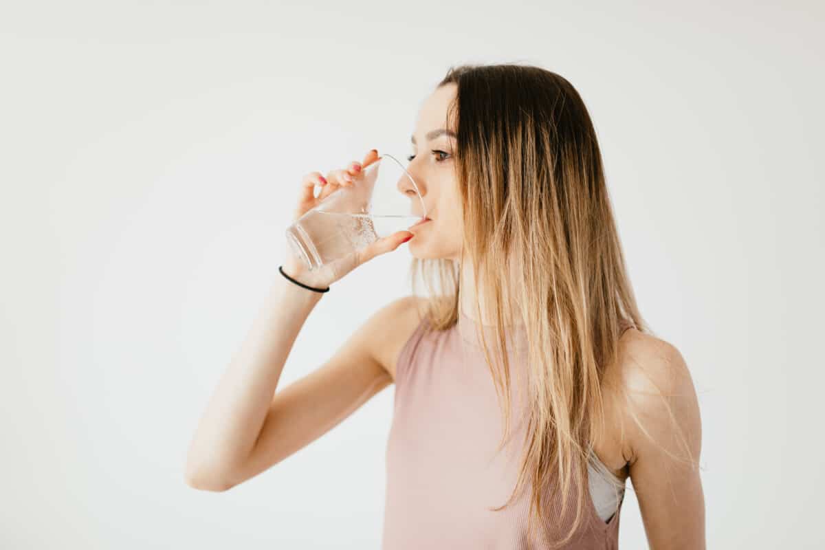 Young woman drinking glass of cold pure water